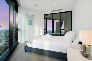 een slaapkamer met een wit bed en grote ramen bij Boutique 3B2B2Carpark Carlton Garden at Doorstep in Melbourne
