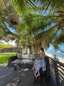 a woman sitting on a couch under a palm tree at Elysium in Unawatuna