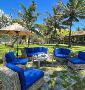 a patio with blue chairs and an umbrella at Elysium in Unawatuna