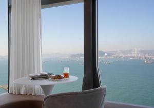 a table with a glass of orange juice and books and a window at One-Eight-One Hotel & Serviced Residences in Hong Kong
