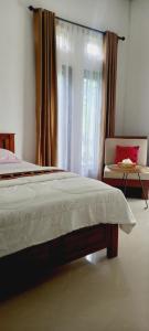 1 dormitorio con 1 cama, 1 silla y 1 ventana en Inang Amang Homestay en Labuan Bajo