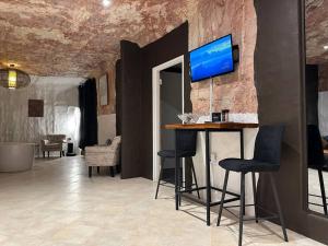a room with a bar with chairs and a tv on the wall at Cozy Cave Coober Pedy in Coober Pedy