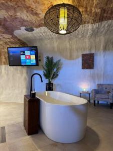 a large bath tub in a room with a tv at Cozy Cave Coober Pedy in Coober Pedy