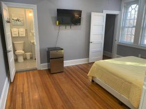 ein Schlafzimmer mit einem Bett und einem TV sowie ein Badezimmer in der Unterkunft Cozy 2BD/2BA Apartment in Baltimore