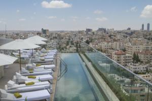 una piscina con sedie a sdraio e ombrelloni bianchi di Regency Palace Amman ad Amman