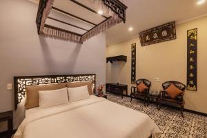 a bedroom with a large bed and two chairs at HueNam Residence in Hue
