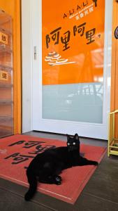 um gato preto deitado num tapete à frente de uma porta em A-Li A-Li Homestay em Chiayi City