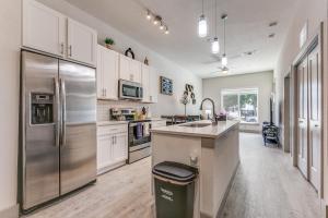 uma cozinha com um frigorífico de aço inoxidável e armários brancos em Lush Downtown Condo on RiverWalk #1100 em San Antonio