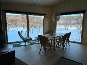 een eetkamer met een tafel en stoelen en een groot raam bij Villa Aitti in Utsjoki