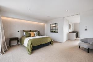 a bedroom with a large bed and a chair at Luxury in Paradise - Sea views and Beach in Mount Maunganui
