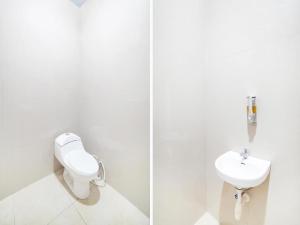 Baño blanco con aseo y lavamanos en Sg Premium Guest House By Helocus, en Medan