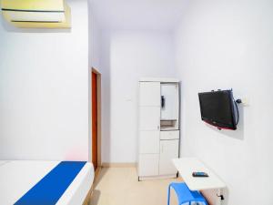 um quarto de hospital com uma cama e uma televisão em Sg Premium Guest House By Helocus em Medan