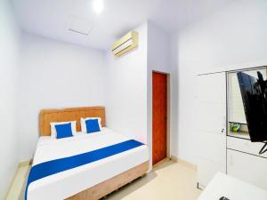 1 dormitorio con 1 cama con almohadas azules y TV en Sg Premium Guest House By Helocus, en Medan