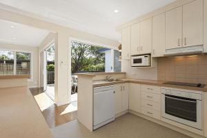 a kitchen with white cabinets and a large window at Curragundi in Point Lonsdale