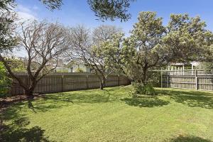 a yard with a fence and some trees at Curragundi in Point Lonsdale