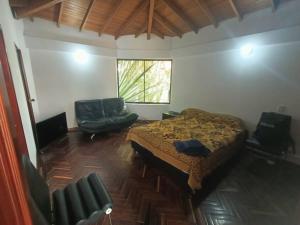 a bedroom with a bed and a couch and a window at Casa Campestre Poblado para 8 in Medellín