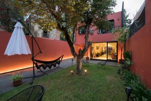 einen Garten mit einem Baum und einer Hängematte neben einem Gebäude in der Unterkunft Tonalli Casa Boutique in Mexiko-Stadt