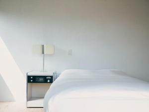una camera bianca con letto e comodino di 范冰冰 ファン・ビンビン a Shimo-ōzu