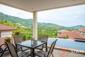 a balcony with a glass table and chairs and a swimming pool at Chaweng Hill Apartment 2Br & Private Pool in Koh Samui 