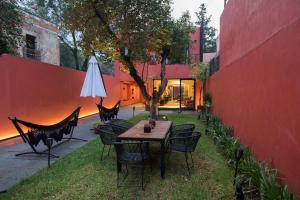 einen Tisch und Stühle in einem Hof neben einer roten Wand in der Unterkunft Tonalli Casa Boutique in Mexiko-Stadt