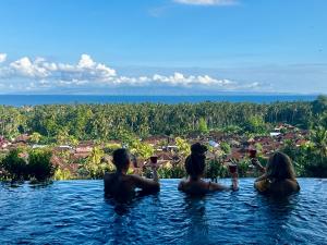a group of people sitting in a infinity pool with drinks at Maya Villa in Candidasa