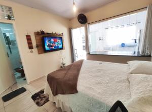 1 dormitorio con 1 cama y TV en la pared en Kitnet Sol - Mobiliada, en Belo Horizonte