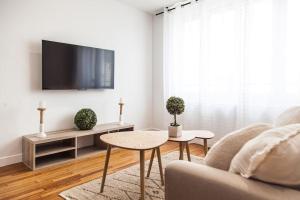 a living room with a couch and a tv at Côté cour - gare/centre, neuf, clim in Châteauroux