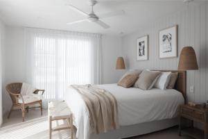 1 dormitorio blanco con 1 cama y 1 silla en Treasure on Trestles - Premium Holiday Home hosted by Holiday Management, en Casuarina