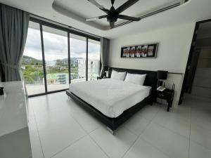 a bedroom with a bed and a large window at Twin Sands Resort Penthouse in Patong Beach