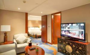 a living room with a television and a room with a bed at Wyndham Grand Plaza Royale Ningbo in Ningbo