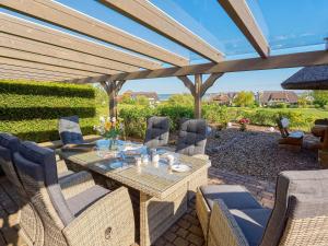 eine Terrasse mit einem Tisch und Stühlen unter einer Pergola in der Unterkunft Reethaus Zickersche Berge - WG 02 mit Kamin und Terrasse in Gager