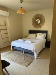 1 dormitorio con 1 cama blanca grande y espejo en Pool apartment 5 minutes walk from beach, en Porto Rafti