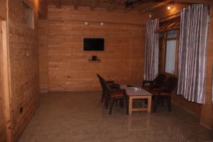 uma sala de jantar com uma mesa e cadeiras e uma televisão em Hotel Mannat Sach Pass em Tisa