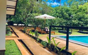 un patio con sombrilla junto a una piscina en The Countryside Udawalawe en Udawalawe