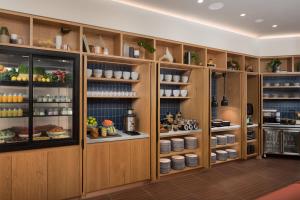 a kitchen with wooden cabinets and shelves with food at Rydges Geelong in Geelong