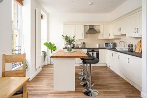 a kitchen with white cabinets and a wooden counter top at Spacious 2 Bedroom House With Stunning Views in Bath