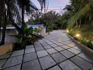 a walkway in front of a house with palm trees at Wild Orchid 5BHK Villa & Eco Cottages in Sancoale Valley in Sancoale