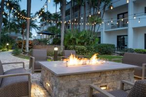 a fire pit in a patio with chairs and a building at Courtyard by Marriott West Palm Beach in West Palm Beach