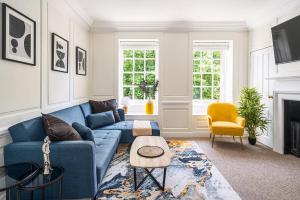uma sala de estar com um sofá azul e uma cadeira amarela em Stunning 3 Bedroom Period City Centre Apartment em Bath