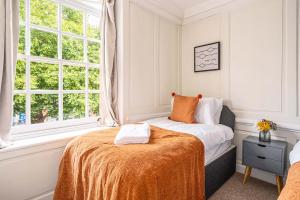 a bedroom with a bed with an orange blanket on it at Stunning 3 Bedroom Period City Centre Apartment in Bath