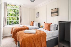 a bedroom with two beds with orange sheets and a tv at Stunning 3 Bedroom Period City Centre Apartment in Bath
