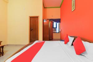 OYO Flagship 86687 Hotel Anandlok في هالدوانى: غرفة نوم بسرير كبير وبجدران حمراء