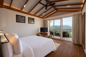 ein Schlafzimmer mit einem großen weißen Bett und einem Balkon in der Unterkunft Welcomhotel By ITC Hotels, Jim Corbett in Marchula
