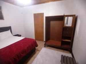Un dormitorio con una cama y un armario de madera. en Budget Room, en Pietermaritzburg