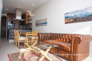 Escape Condominiums Beachfront Suites - Mae Phim في رايونغ: غرفة معيشة مع أريكة جلدية وطاولة