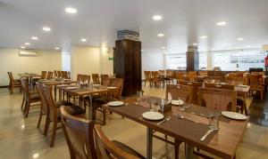 comedor con mesas y sillas de madera en Treebo Tryst Rose Mallow en Nueva Delhi