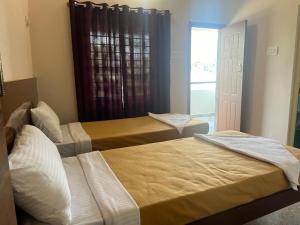 two beds in a room with a window at RT Service Apartment Villas in Velankanni