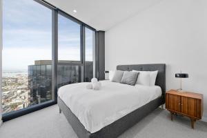 1 dormitorio con 1 cama blanca grande y ventanas grandes en Sub Penthouse Southbank Apartment - 3BR, en Melbourne