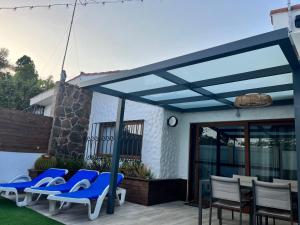 a blue pergola on a patio with chairs and a table at Bungalow Yumbo in Playa del Ingles
