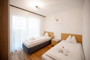 two beds in a room with a window at T-Collection Premium Apartments in Vipiteno